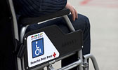 Foto: Auschnitt eines Rollstuhls mit der Hand seines Fahres auf der Lehne.